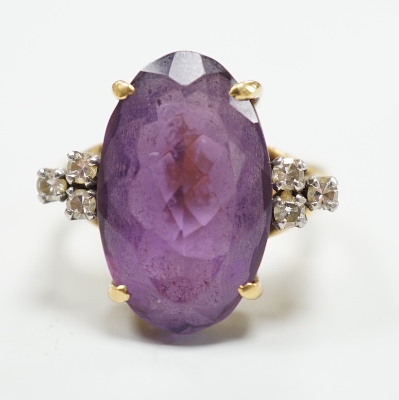 A yellow metal and oval cut amethyst set dress ring, with six stone diamond set shoulders, size O, gross weight 9.6 grams.